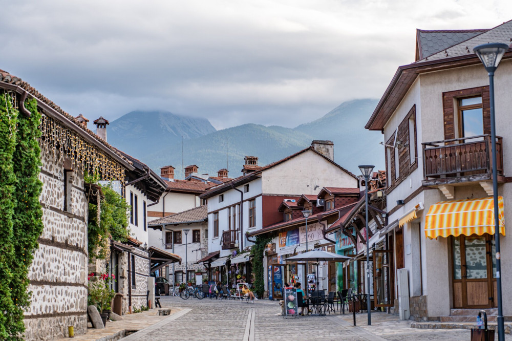 Bansko főutcájának igényesen felújított épületei, háttérben a Pirin-hegység csúcsai