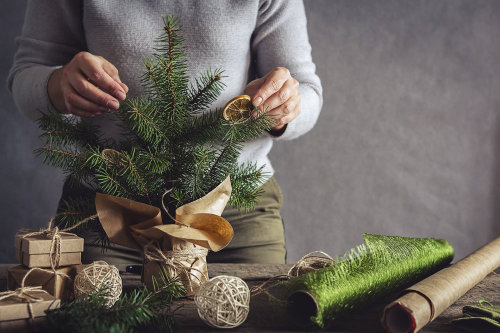 Christmas and zero waste, eco friendly packaging. Woman is wrapping gifts in craft paper on a wooden table, ecological Christmas holiday concept, eco decor