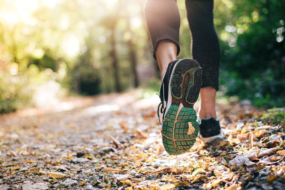 Closeup of running shoe of the person running in the nature with beautiful sunlight.