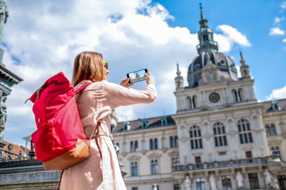 Nő turista fotóz egy épületet a telefonjával